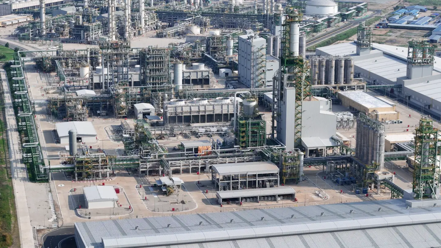 Vista de drone de uma unidade de processo: colunas com estrutura de escadas, racks de tubulação, trocadores de calor, torres de resfriamento e silos